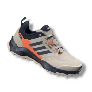 Pair of rugged trail sneakers in beige with orange and navy accents, featuring a thick grip outsole and cushioned sole designed for outdoor and all-terrain use.