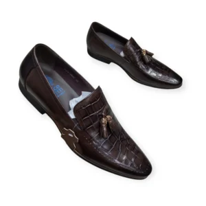 a pair of coffee brown classic leather formal loafers on the white background. The shoes features a a classic tassel detailing, sleek finish and decorative crocodile accents on the vamp that adds a touch of refinement, perfect for both formal and casual occasions.