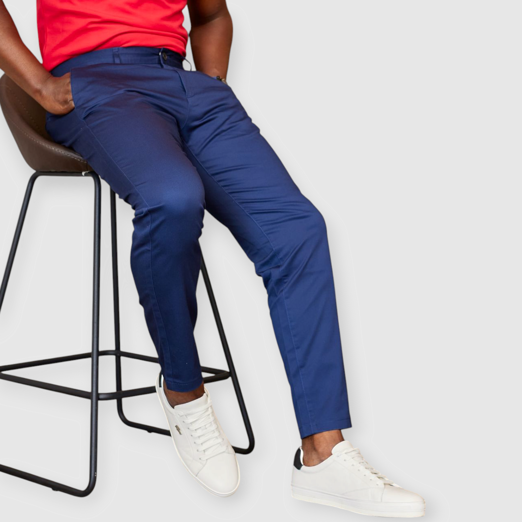 a man wearing navy blue essential khaki pants with black sneakers seated on a raised chair