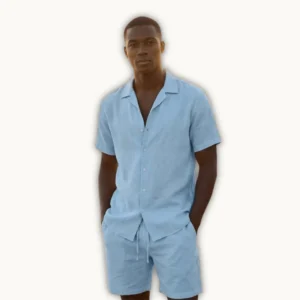 Man wearing a light blue linen shirt and shorts. Short-sleeve button shirt and drawstring shorts, styled for beach and summer vacation wear