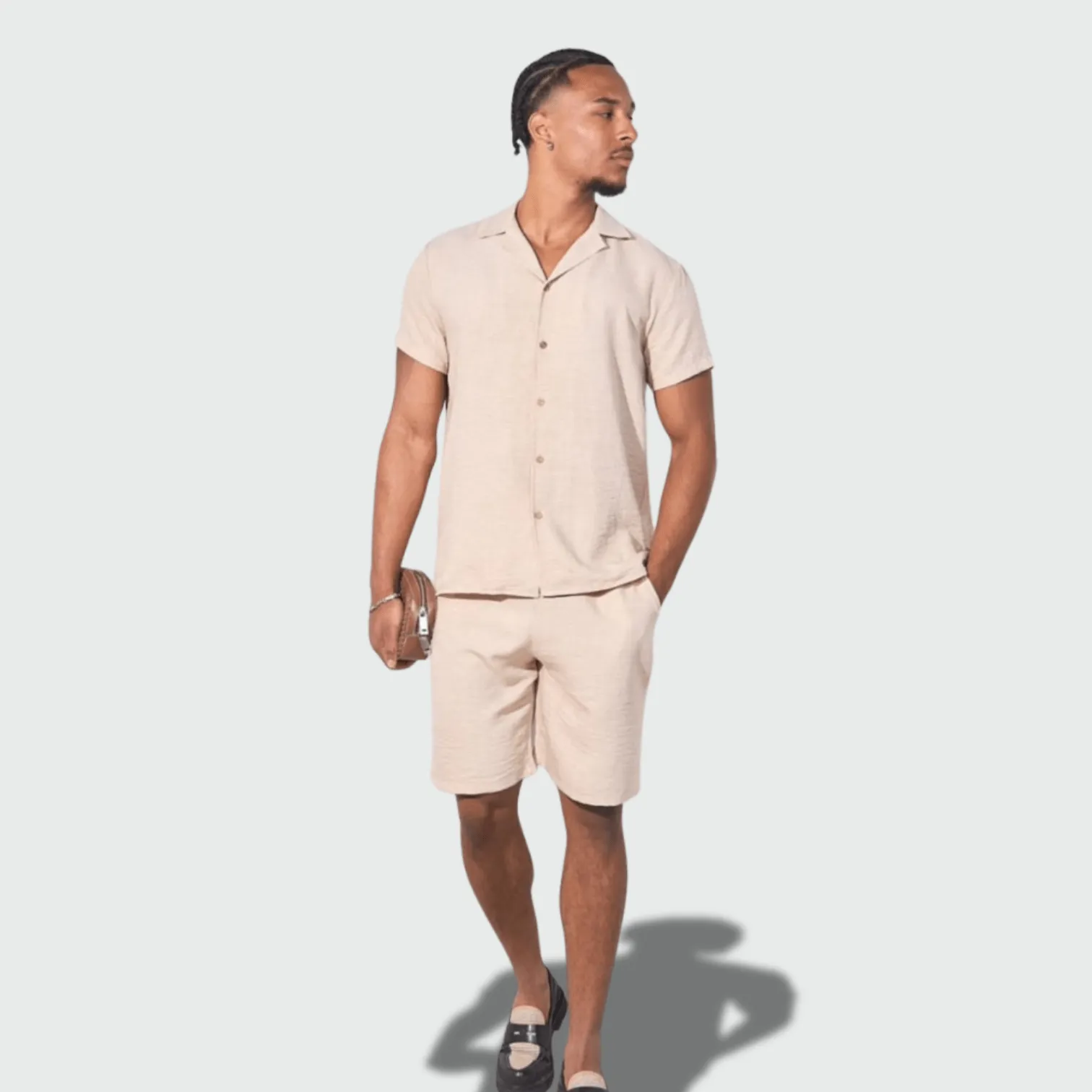 Man wearing a beige linen shirt and shorts, styled for summer resort and casual wear