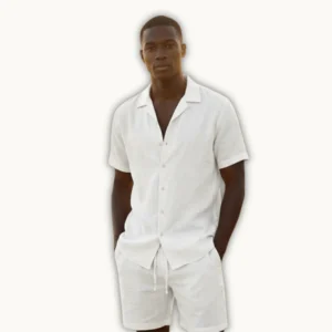 Man wearing a white linen short set with short-sleeve button shirt and drawstring shorts, styled for beach and summer vacation wear