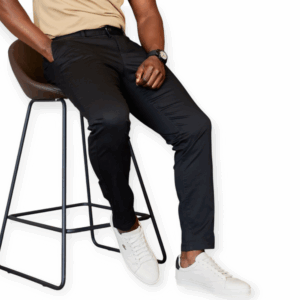 a man in black mens khaki pants and white sneakers seating a raised chair. he looks elegant in the black pants.