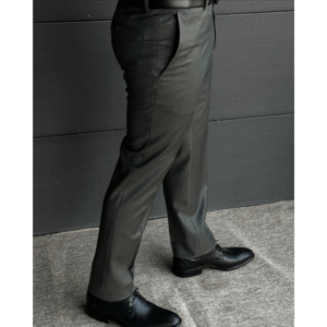 A man wearing grey wool formal trousers paired with black leather dress shoes, photographed in a modern indoor setting.