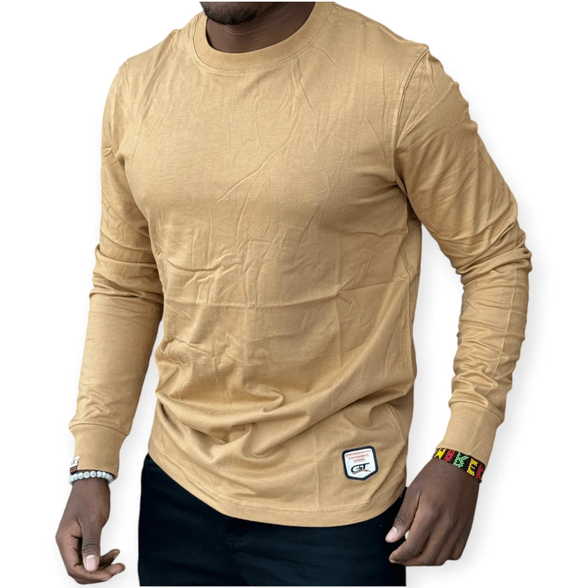 man wearing a beige long sleeved men's cotton t-shirt with a classic crew neck design, styled casually with dark jeans for everyday wear