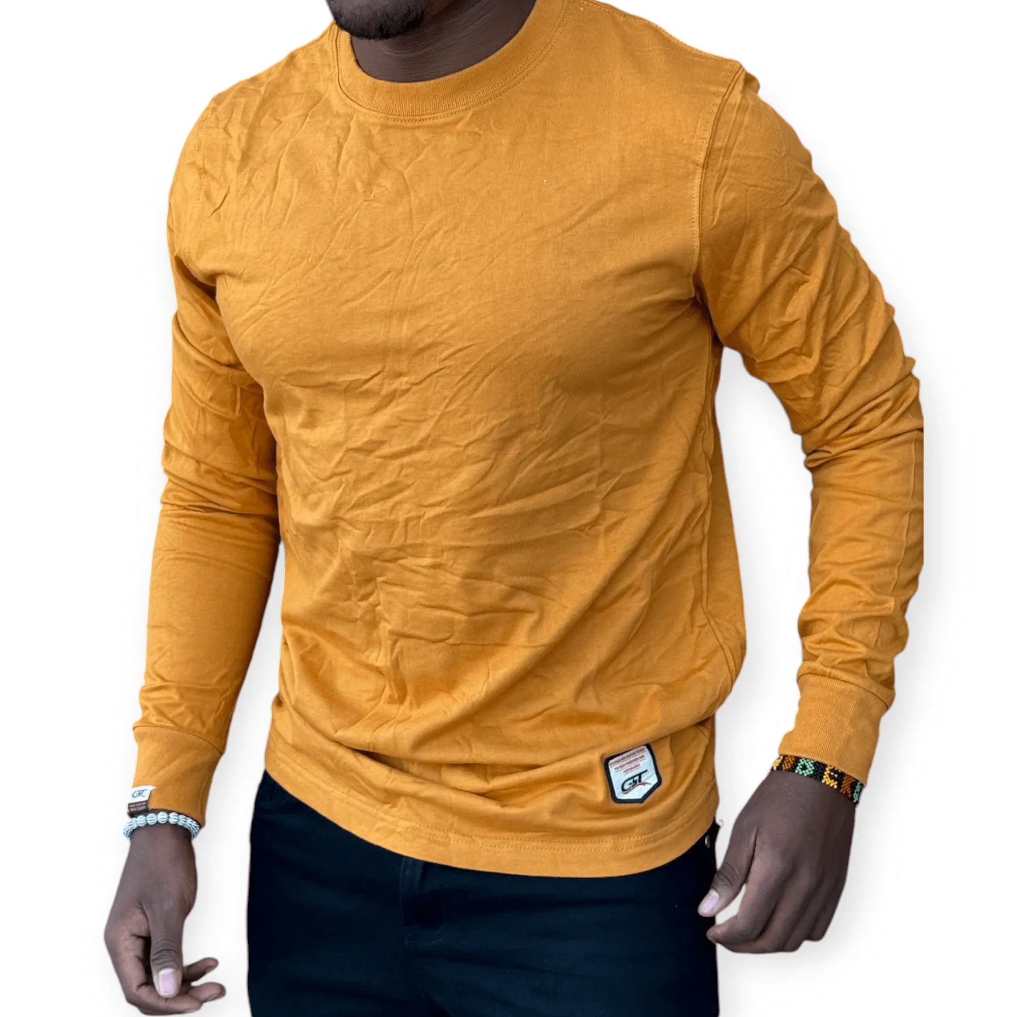 Man wearing a mustard yellow cotton t-shirt with a slim fit, styled casually with dark jeans for everyday wear
